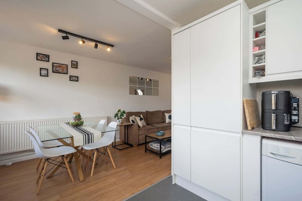 Un espacio habitable compacto con kitchenette, comedor y zona de estar.