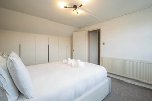 Hotellihuone, jossa on suuri sänky, kattovalaisin ja patteri.