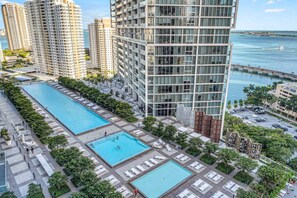 Um edifício alto com piscina no terraço e vista para o oceano.