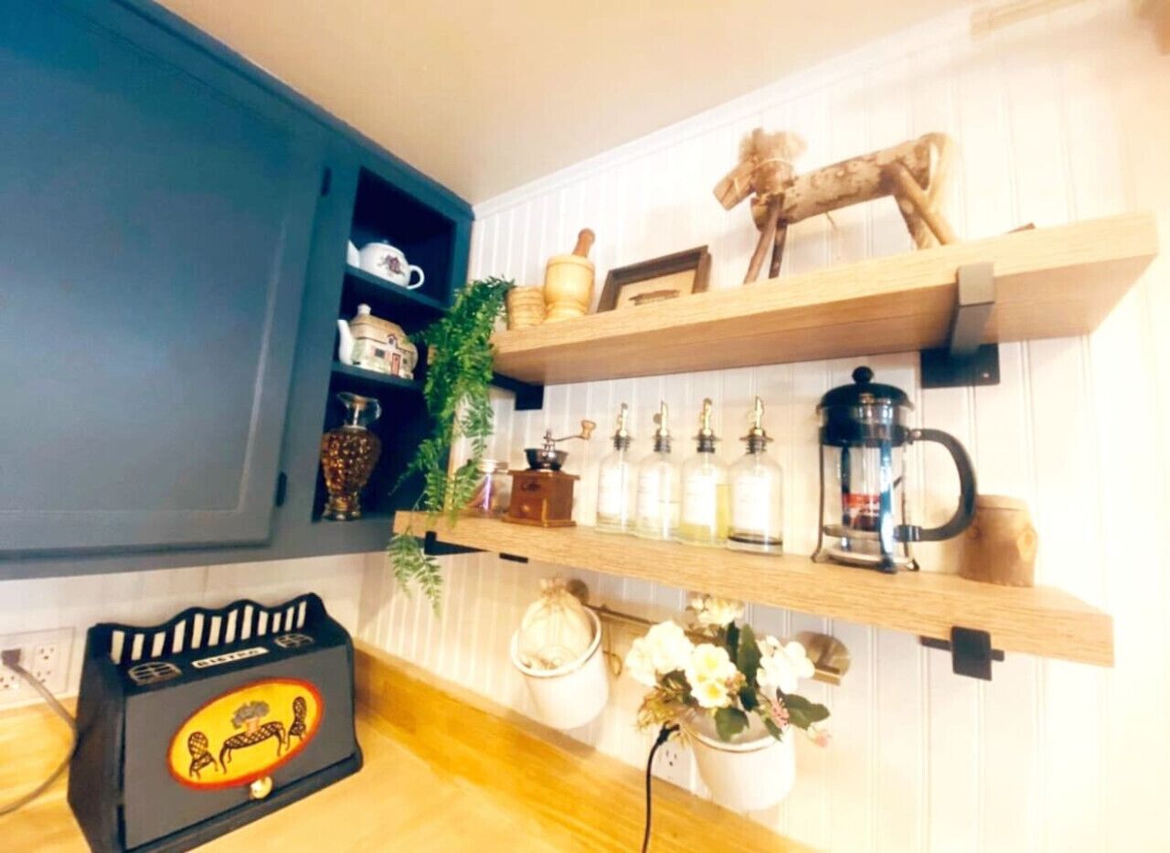 A kitchen with wooden shelves holding kitchenware, a coffee maker, and a decorative horse figure.