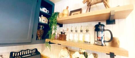 A kitchen with wooden shelves holding kitchenware, a coffee maker, and a decorative horse figure.