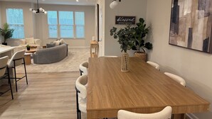 Un comedor moderno con una mesa de madera, sillas blancas y una planta grande.