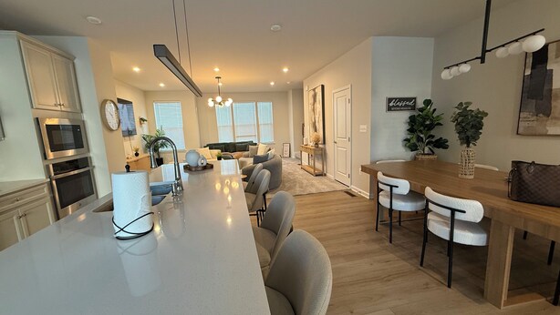 Una cocina moderna con una isla central, electrodomésticos integrados y una zona de comedor con mesa y sillas de madera.