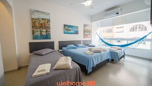 Una habitación de hotel con dos camas, una hamaca y obras de arte en las paredes.