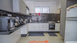 Una cocina moderna con cafetera, hervidor, estufa y refrigerador.