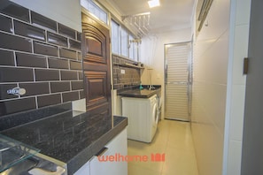 A compact kitchen with dark tiled backsplash, a built-in oven, and a washing machine.