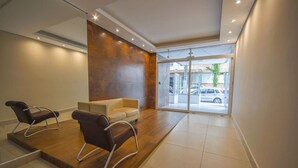 Un área de espera moderna con dos sillones de cuero, un sofá y un gran ventanal que da al exterior.