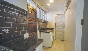 A compact kitchen with dark tiled backsplash, a built-in oven, and a washing machine.
