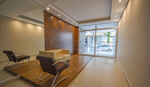 A modern waiting area with two leather chairs, a sofa, and a large glass door leading outside.