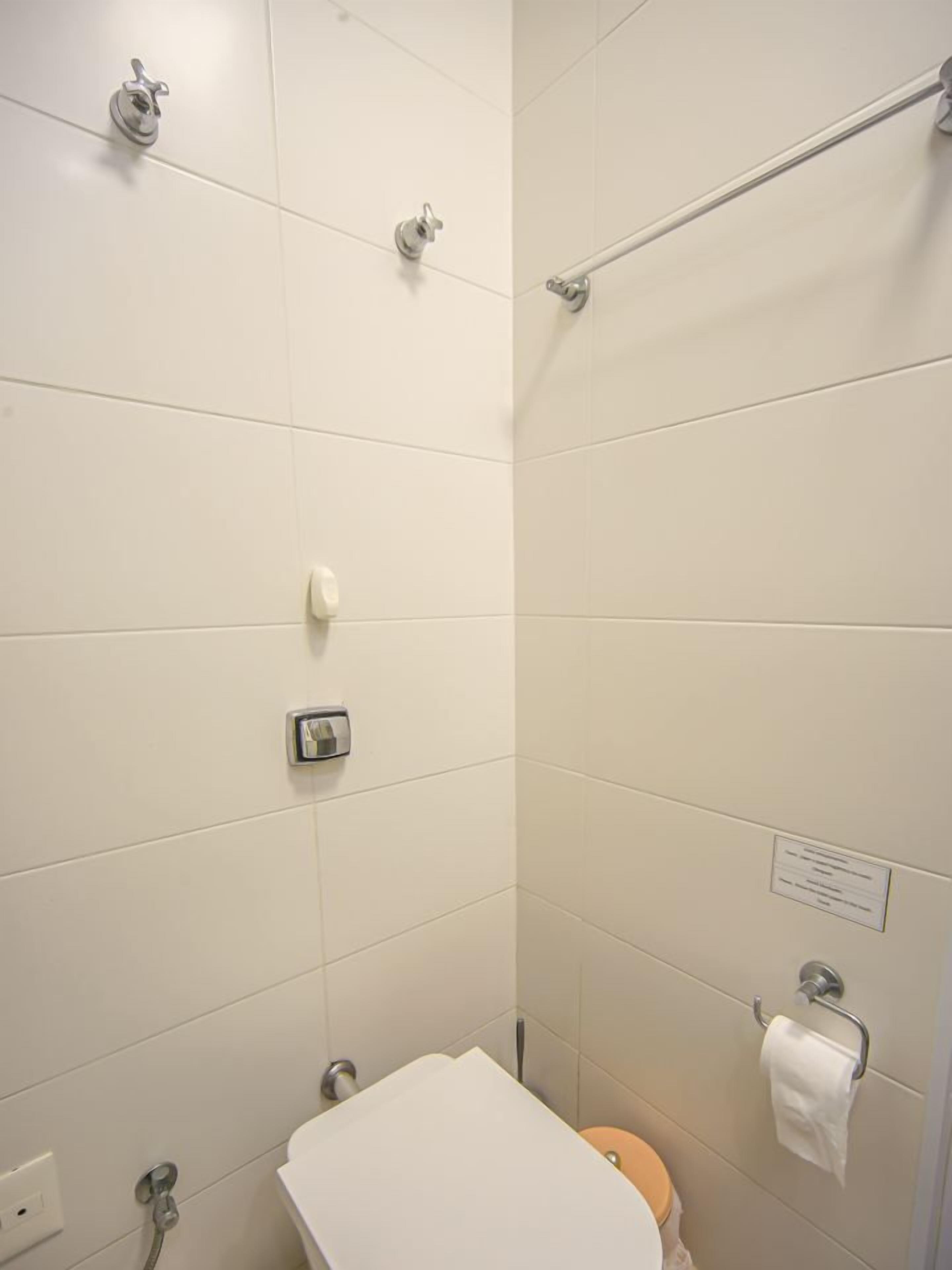 Ein kleines, sauberes Badezimmer mit Toilette, Dusche und Handtuchhalter.