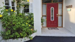 Una casa con puerta roja, un pequeño porche y un cartel que dice "ESTRADA".