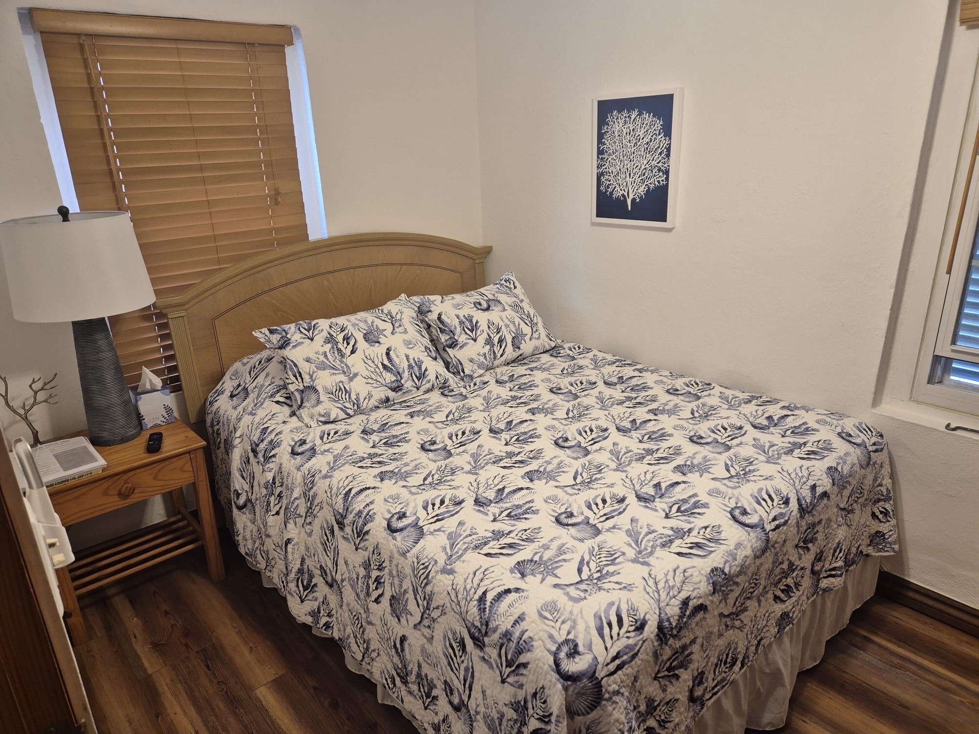 Une chambre à coucher avec un lit, une table de chevet, une lampe et un tableau encadré au mur.
