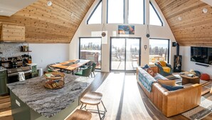 Un loft spacieux avec de hauts plafonds, une cuisine équipée d’appareils modernes, un coin repas, un salon doté d’un grand canapé et une cheminée.