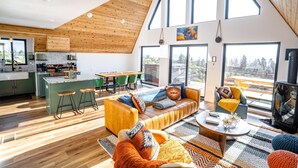 Un loft moderne comprenant une cuisine, un coin repas et un espace de vie, le tout doté de grandes fenêtres et d’un plafond haut.