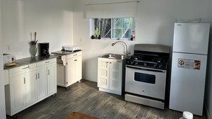 Una cocina con armarios blancos, estufa, lavabo y refrigerador.