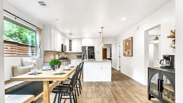 Een moderne keuken met witte kasten, een centraal eiland en een zithoek met een bank.