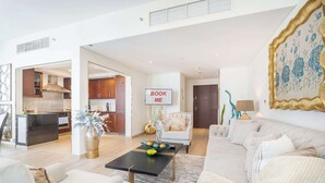 A modern living room with a sofa, coffee table, and a dining area with a kitchen in the background.