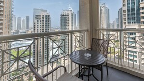 A balcony with a view of high-rise buildings, a round table, and wicker chairs.