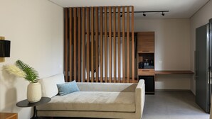 Una sala moderna con un sofá, una mesita auxiliar, un jarrón decorativo y un separador de madera.
