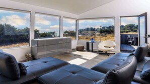 Un salon moderne avec une grande fenêtre, un canapé, une petite table et un fauteuil.