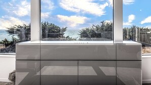 Une chambre moderne dotée d’une grande fenêtre donnant sur une vue imprenable sur la côte.
