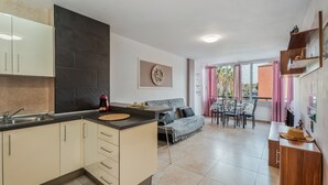A modern kitchen with a dining area, a sofa, and a table with chairs. - 'Chasna' Holidays with Shared Pool, Shared Garden and Wi-Fi (Arona)