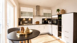 A modern kitchen with white cabinets, a black dining table, and a patterned rug. - Your exclusive penthouse in a perfect location - pure luxury and relaxation with its own (Norderney)