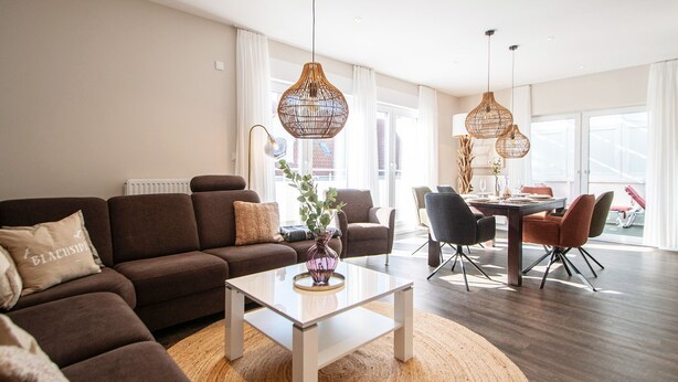 A modern living room with a sofa, coffee table, dining table, and chairs. - Your exclusive penthouse in a perfect location - pure luxury and relaxation with its own (Norderney)