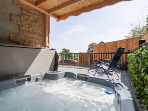 A hot tub on a wooden deck with a brick wall and a wooden fence in the background. - Woodside (Scarborough)