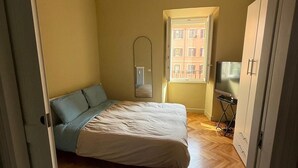 Ein Schlafzimmer mit Bett, Heizkörper, Fernseher und Kleiderschrank.