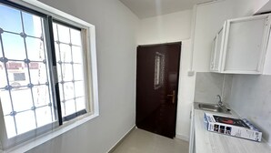 A small, clean room with a window, a door, and a kitchenette area. - Private Studio attach washroom, kitchen, Terrace (Abu Dhabi)