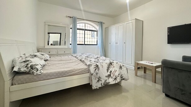 A bedroom with a bed, a wardrobe, a TV, and a small table. - Private Studio attach washroom, kitchen, Terrace (Abu Dhabi)