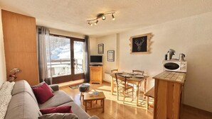 A cozy living room with a sofa, a dining table, and a kitchen area with a microwave.