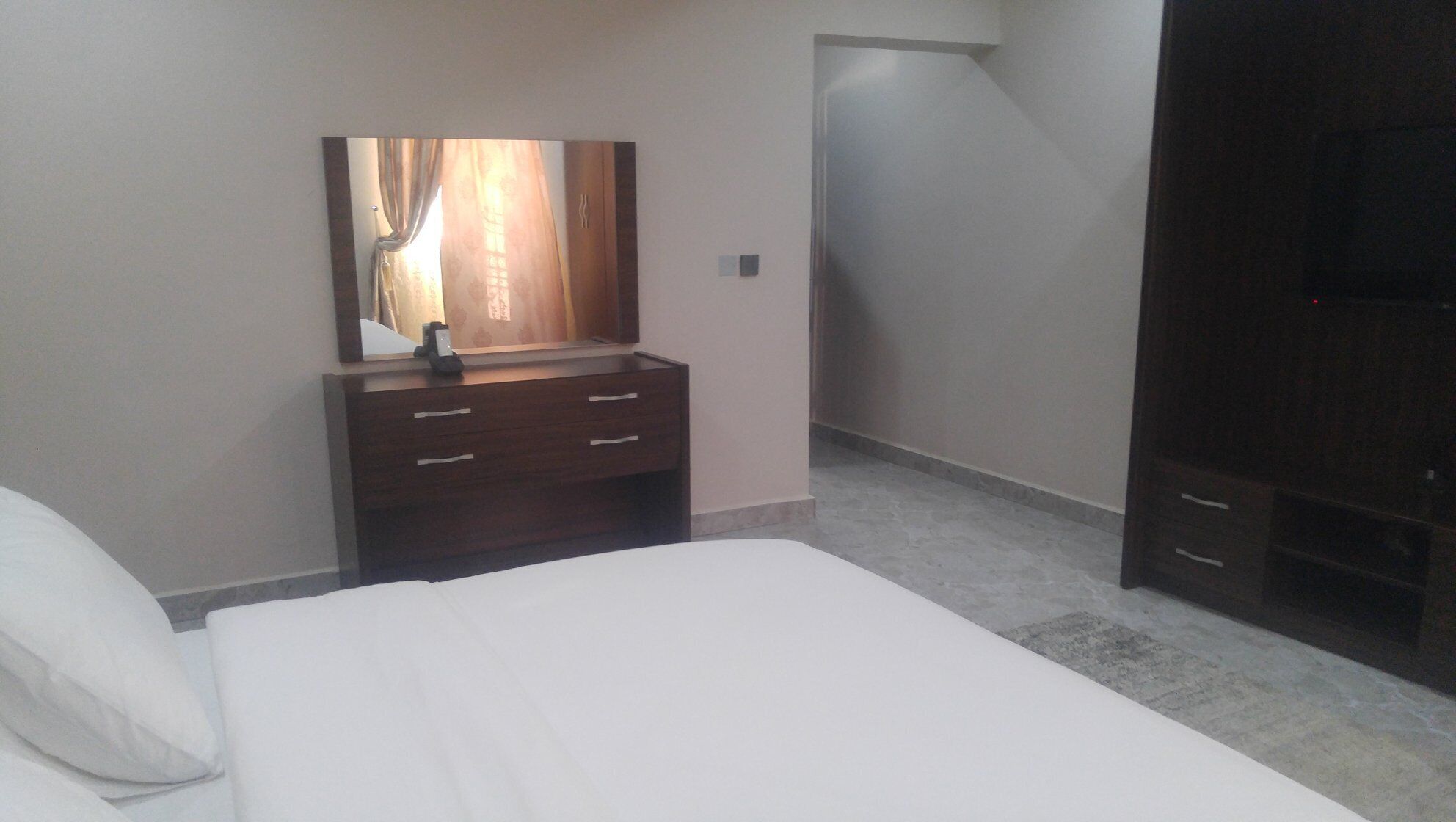A bedroom with a bed, a dresser, a mirror, and a wardrobe.