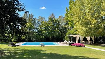 Ein Pool, umgeben von üppiger Vegetation und einem Pavillon mit Sitzgelegenheiten.