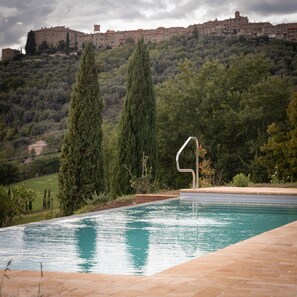 A swimming pool with a clear view of a hillside and a building in the background.