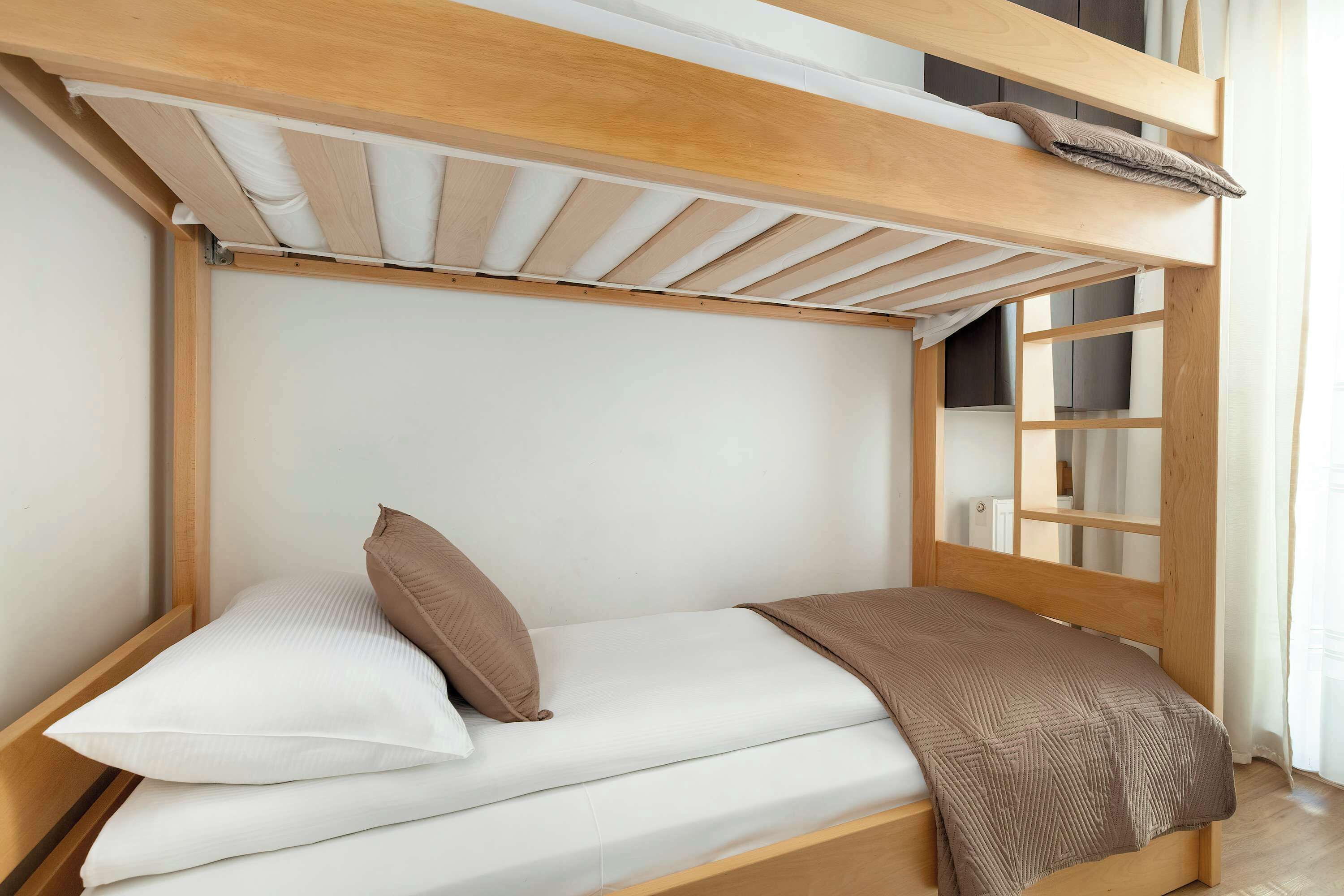 Un letto a castello con struttura in legno, un materasso bianco e una coperta marrone.