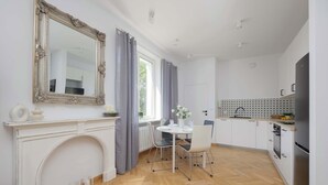 A modern kitchen with white cabinets, a built-in oven, and a dining area with a white table and chairs.
