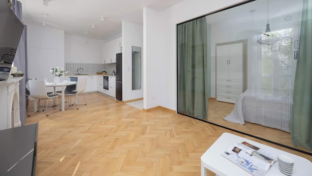 A modern apartment with a dining area, kitchen, and a large sliding glass door leading to a balcony.