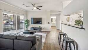 A modern living room with a grey sofa, a TV, and a ceiling fan. - Rocky Mountain Haven w/ king bed, pool & hot tub (Castle Rock)