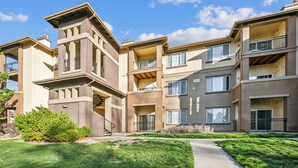 A multi-story residential building with balconies, a clear sky, and a well-maintained lawn. - Rocky Mountain Haven w/ king bed, pool & hot tub (Castle Rock)
