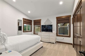 A bedroom with a large bed, a dresser, a television, and a window with a view. - Treetop Escape: HotTub, BBQ, In/Outdoor Fireplace (Cle Elum)