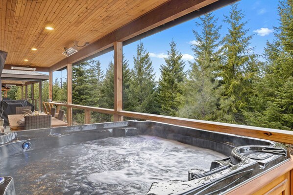 A hot tub with a wooden deck and a view of a forest. - Treetop Escape: HotTub, BBQ, In/Outdoor Fireplace (Cle Elum)