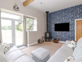 Ein modernes Wohnzimmer mit einer großen Couch, einem Kamin und einem an der Wand montierten Fernseher.