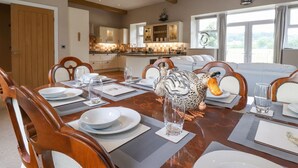 A dining area with a wooden table set for six, surrounded by chairs. A decorative bird sculpture is on the table. - The Gatehouse (Kendal)