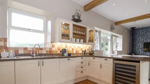 A modern kitchen with white cabinets, a granite countertop, and a built-in dishwasher. - The Gatehouse (Kendal)