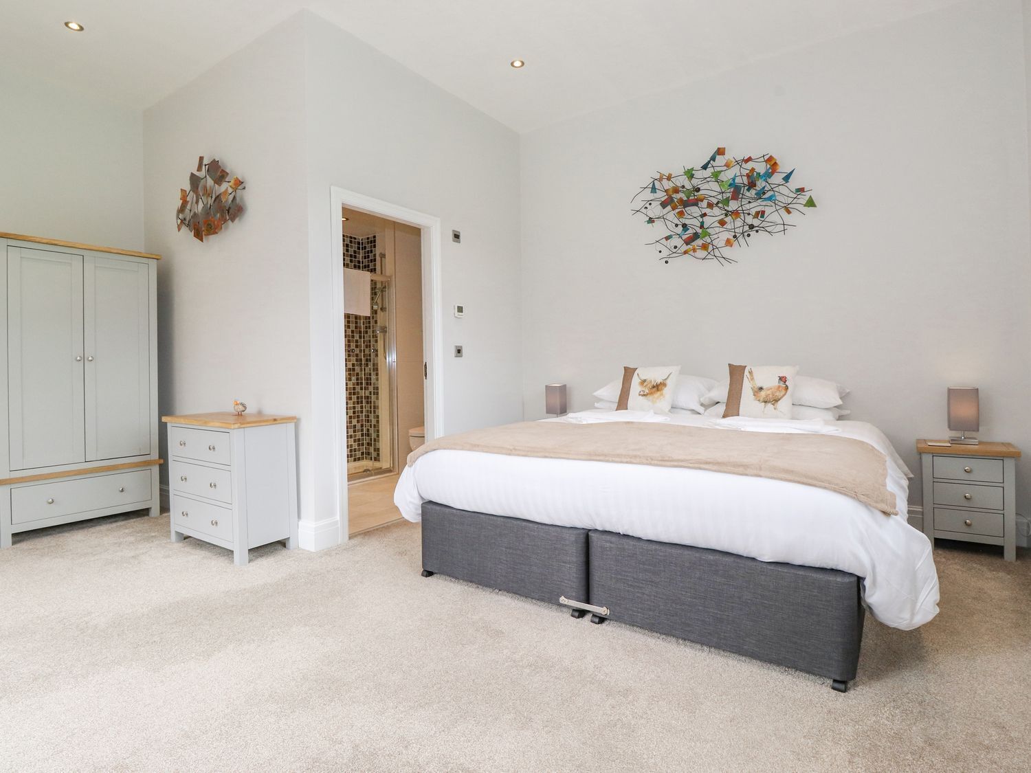 Een slaapkamer met een groot bed, nachtkastjes, een kledingkast en een douchehoek.