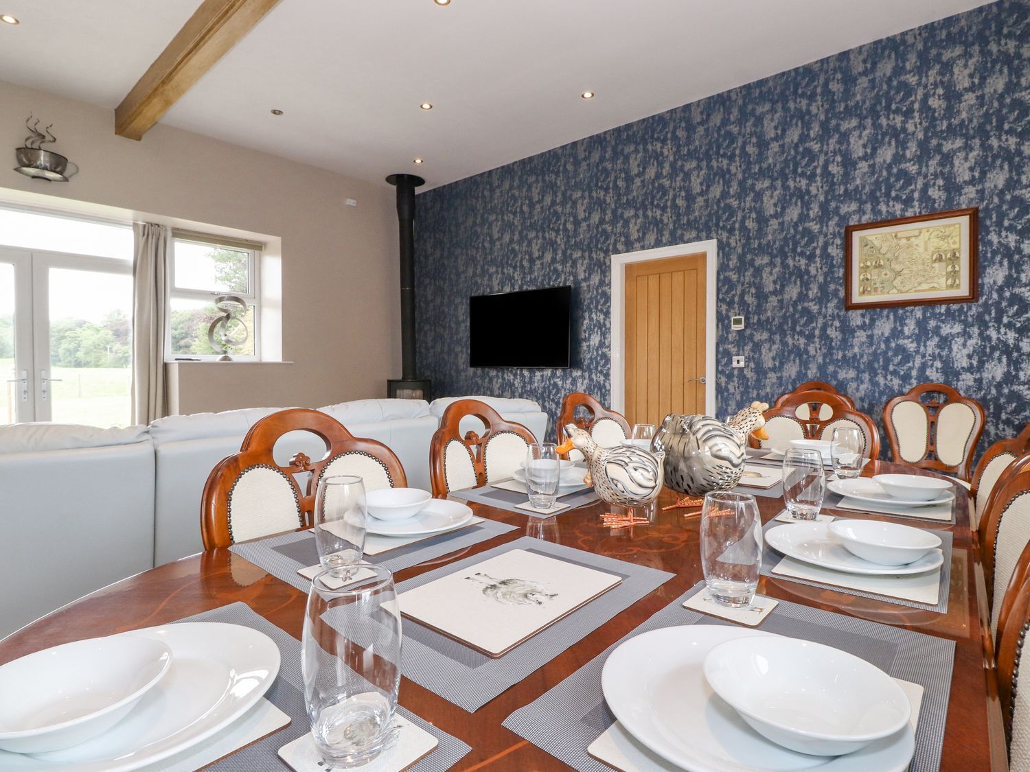 A dining area with a large table set for a meal, surrounded by wooden chairs with cushioned seats.
