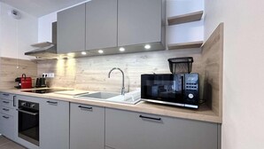 Une cuisine moderne avec des meubles gris, une hotte en acier inoxydable, un four à micro-ondes et un évier.