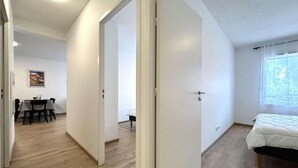 Une pièce moderne et bien éclairée, dotée d’un plancher en bois, d’un lit et d’un coin repas avec une table et des chaises.